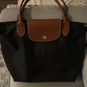 Longchamp black purse with leather handle and snap.